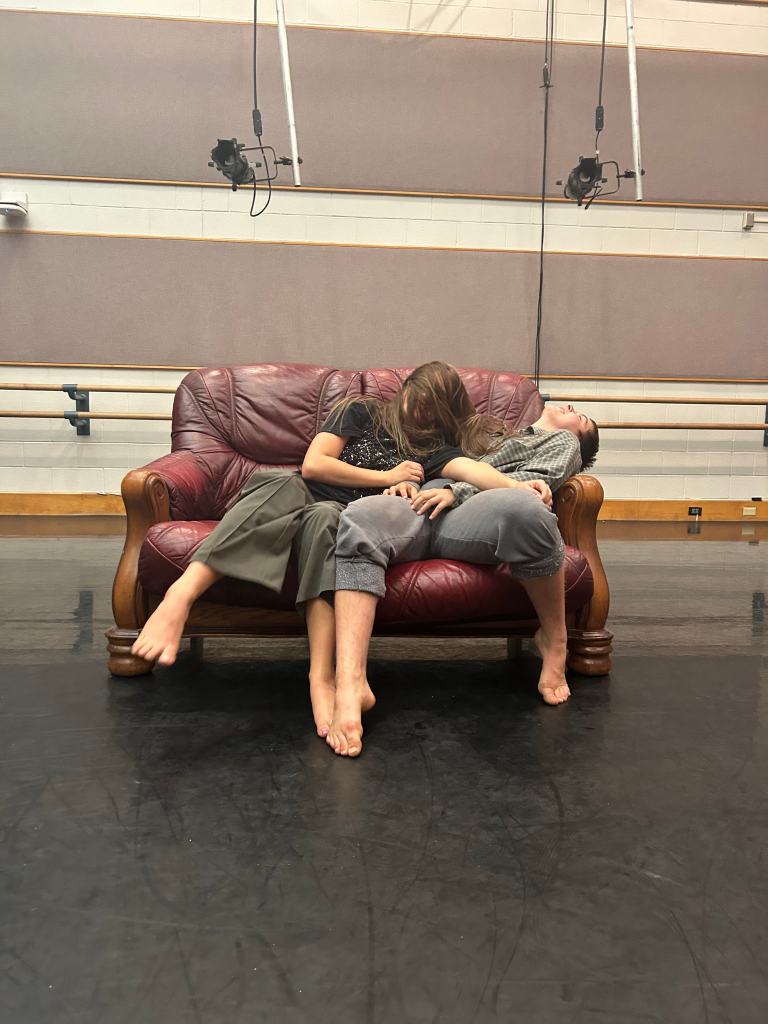 Two dancers on a red couch. 